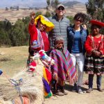 coppia di turisti in posa con un gruppo di abitanti delle Ande