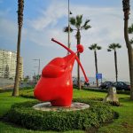 statua rossa in un parco di palme