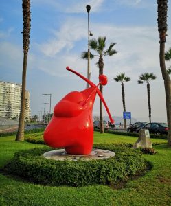 statua rossa in un parco di palme